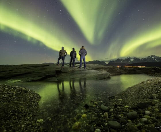 People standing in front of Aurora Borealis